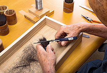 竹宝堂の筆づくり：根元の余分な毛を切り取る