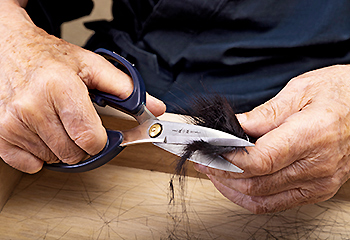 竹宝堂の筆づくり：根元の余分な毛を切り取る